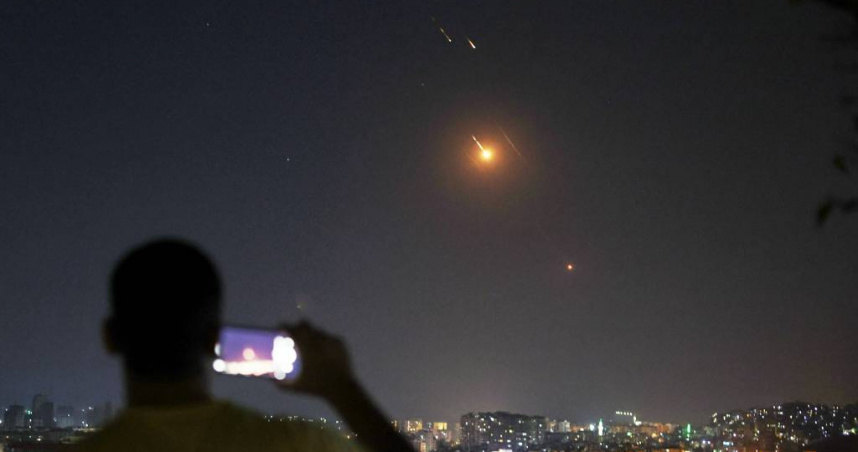 一名男子在敘利亞拍照，畫面是6月18日清晨，伊朗朝以色列發射的飛彈。（圖／美聯社）