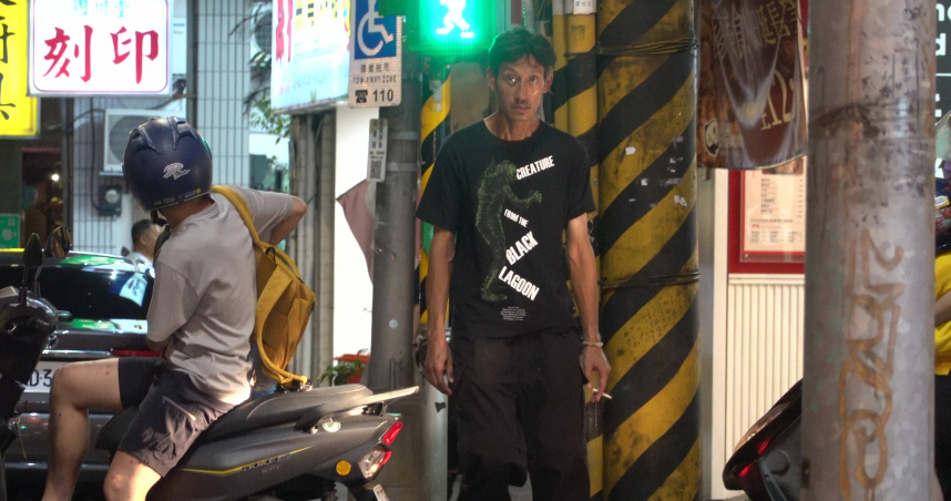 唐治平在南港附近的捷運站綠地緩緩繞圈散步，面無表情且動向隨意不定。（圖／本刊攝影組）