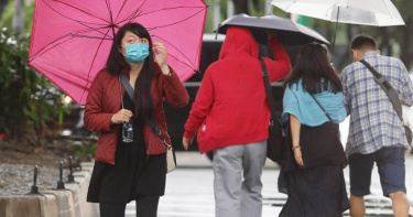 颱風尼莎來襲，行人撐著傘冒雨外出。（圖／中國時報記者季志翔攝）