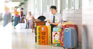 專家預料若不大量招聘教師,5、6年後可能師資不足。圖為一位即將上場應試的考生坐在考場門口複習試教的內容,身旁擺放了各種教具。(圖/報系資料照)
