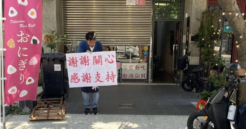 風波發生後，店內業績反而逆勢成長。老闆樋口先生拿著一面寫著「今天飯糰已經賣完」，另一面是「謝謝關心感謝支持」的標語，不斷在店門口向遠道而來卻撲空的顧客鞠躬道謝。（圖／報系資料照）