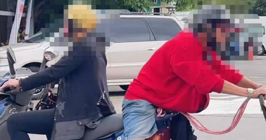 阿伯乘坐在機車後座，但整個人面向後方，雙手拖著載有樹葡萄盆栽的推車一起上。(圖／大溪警分局提供)